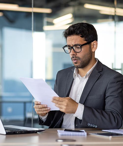 Upset financier investor checking accounts and contracts financial reports, businessman unhappy and disappointed with achievement results at workplace using laptop for paper work.