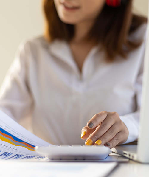 Woman checking an account using a calculator calculating financial numbers.
